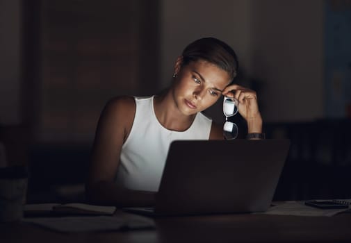 Stress is the ultimate passion killer. a young businesswoman looking worn out while using a laptop during a late night at work.