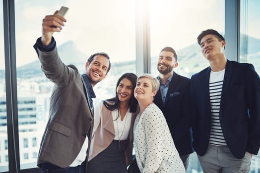 The faces behind the success. a group of businesspeople taking a selfie together in an office.