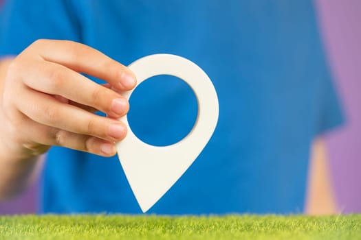 Travel concept. Hand holding pin icon or navigation tag. GPS direction indicator. Location sign in hands. Route laying.