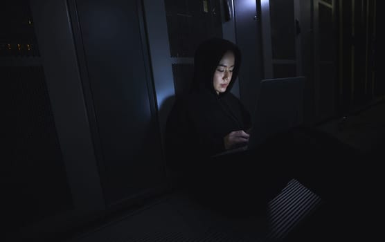 Hacking, laptop and hacker woman in dark server room for coding software, data center crime or cyberpunk intel. Network criminal, person or user in cybersecurity, information technology or ransomware