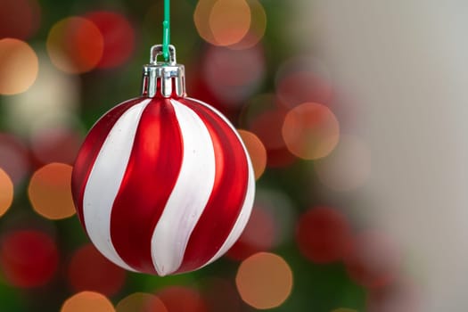 Red and white bauble hanging from a Christmas tree
