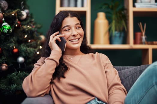 Just calling to say, Merry Christmas. a beautiful young woman using a smartphone on the sofa during Christmas at home.