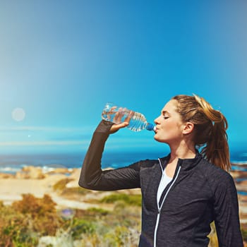 Woman drink water, health and fitness with blue sky, athlete outdoor with hydration and mockup space. Exercise at beach, female person drinking h2o from bottle with workout and break from training