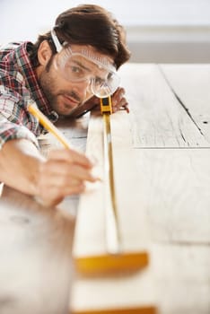 Wood, carpenter man building project and measurement with tape at construction site. Home renovation or furniture design, handyman working on maintenance at workshop and woodwork or handcraft