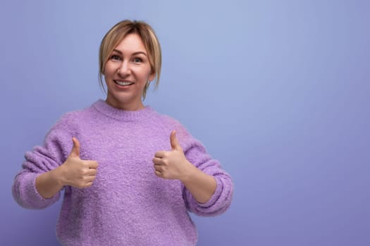 portrait of charming cute blondie woman in lavender sweater holding class like gesture on purple background with copy space