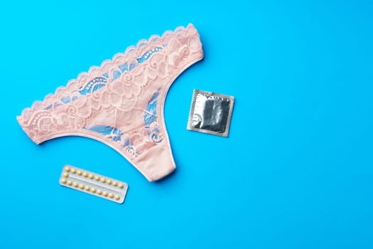 Beautiful women's panties with a condom on a paper background. Safe intimate relationships concept