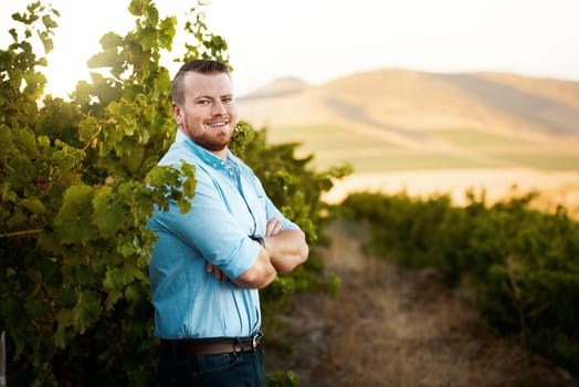 I love every minute on the farm. Portrait of a farmer standing in a vineyard.