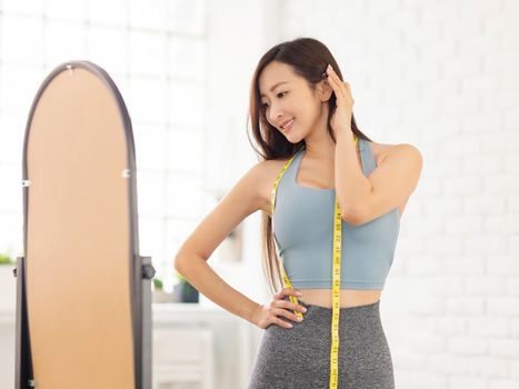 Young woman with tape standing in front of mirror.Weight Loss.