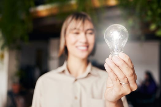 Lightbulb, happy and a woman with light from inspiration, knowledge or ideas at work. Smile, innovation and an employee with power, creativity and energy at a company with optimism and vision