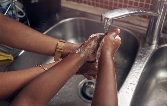 Hands, kitchen sink and mom with kid, closeup and teaching to wash with soap, water and clean to stop germs. Family home, mother and daughter at faucet for cleaning, hygiene and wellness with foam