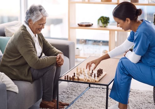 Women, chess and nurse with a senior patient, retirement home and happiness with healthcare. Female person, medical professional and mature lady with employee, nursing and care with games and relax