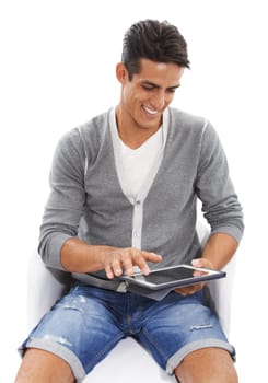 Enjoying modern technology. A handsome smiling young man sitting and smiling while using a ipad against a white background.