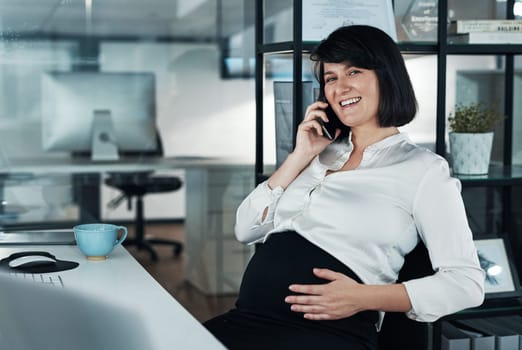 My third trimester wont stop me from working. an attractive pregnant businesswoman sitting alone in the office and using her cellphone.