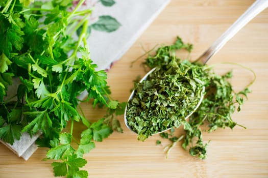 dried parsley in a spoon next to fresh herbs.