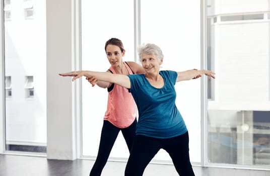 Exercise regularly to keep your muscles loose. a fitness instructor helping a senior woman during a yoga class