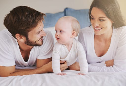 Happy family, mother and father with baby on bed for love, care and quality time together at home. Mom, dad and cute newborn child relaxing in bedroom for happiness, support and development of kids