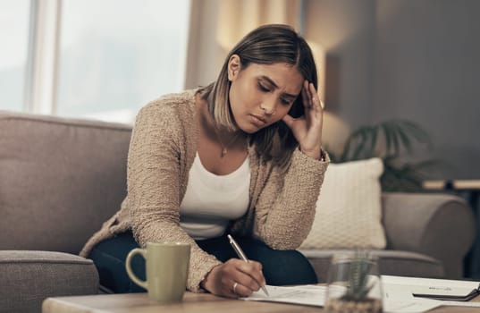 Dont fall into the debt trap. a young woman looking stressed while going over paperwork at home.