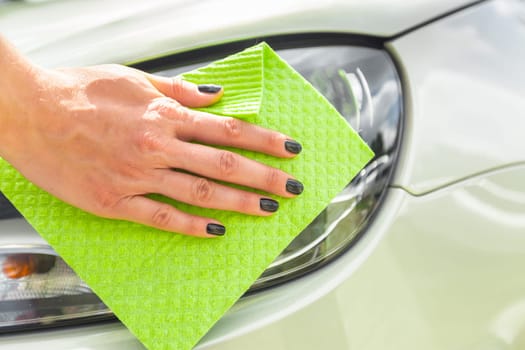 Hand with microfiber cloth cleaning car