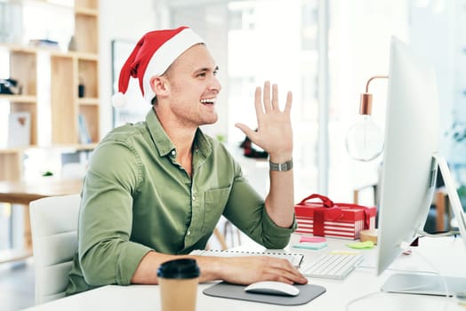 Christmas, business man and hand wave at computer during video call for holiday celebration at office. Happy employee at desk for zoom communication on desktop for festive greeting at workplace