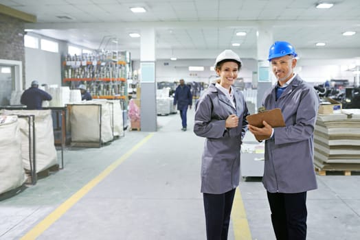 Making logistics look easy. Portrait of two managers in workwear standing on the printing factory floor.