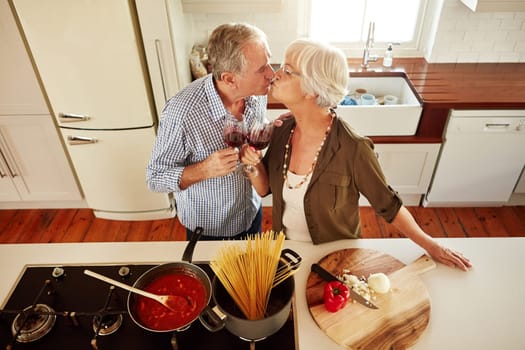 Kiss, wine toast or old couple cooking food for a healthy vegan diet together with love in retirement at home. Top view of senior woman drinking or kissing in kitchen with mature husband at dinner