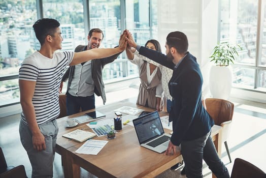 Success is inevitable if everyone gives their best. a diverse group of businesspeople high fiving in an office.