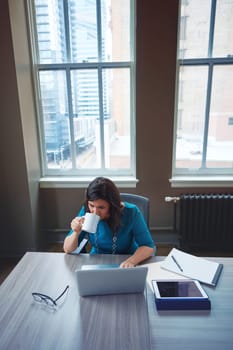 Midday coffee break to keep her refreshed. a businesswoman using a laptop during a break in an office.
