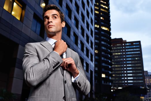 Looking classy in the city. A handsome businessman in a suit standing in a city setting at night.