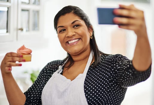 Everyone should try my delicious cupcakes. a woman taking a selfie with her cupcake.