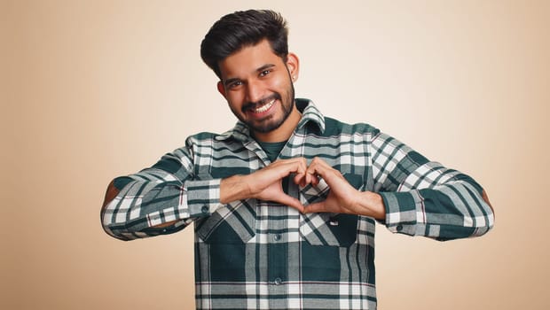 Smiling hindu man makes heart gesture demonstrates love sign expresses good feelings and sympathy