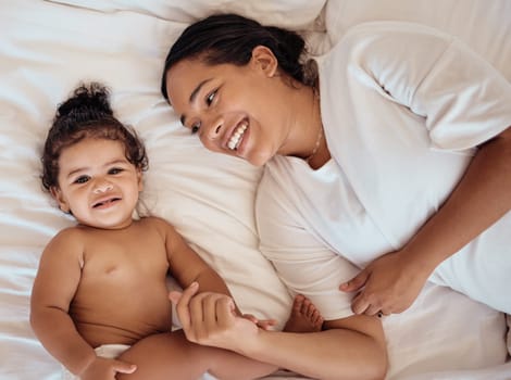 Top view, mama and baby with smile, on bed and happy together for bonding, childhood and loving in home. Love, mom or toddler in bedroom, happiness or positive for wellness, tenderness and motherhood