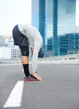 Loosening up for his morning run. a young male jogger stretching in the street before a run.