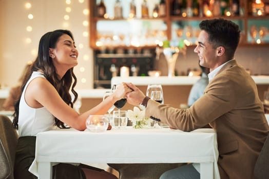 Happy couple holding hands, restaurant and dinner date on Valentines day, celebrate holiday with love, care and romance. Commitment, interracial relationship and man with woman, trust and support