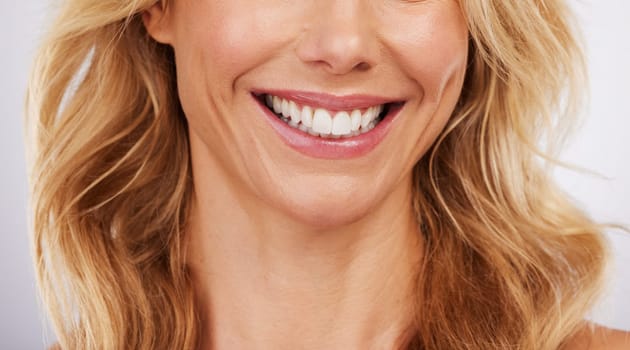 Closeup, smile and woman mouth in studio for dental, hygiene or teeth whitening on grey background. Oral, zoom and cleaning for lady satisfied with bleaching, braces or porcelain veneers results
