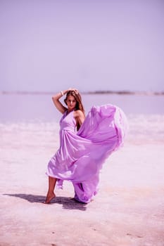 Woman pink salt lake. Against the backdrop of a pink salt lake, a woman in a long pink dress takes a leisurely stroll along the white, salty shore, capturing a wanderlust moment.
