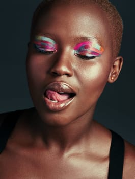 Im sweeter than candy. a beautiful woman wearing colorful eyeshadow while posing against a grey background.