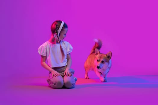 Beautiful little girl playing with cute corgi puppy dog