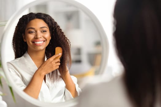 Haircare Routine. Attractive Black Woman Combing Her Beautiful Hair With Brush