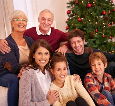 Christmas, happy and portrait of family on sofa for festive, celebration and holiday cheer. Support, relax and smile with people in living room at home for gift giving, xmas and gratitude together