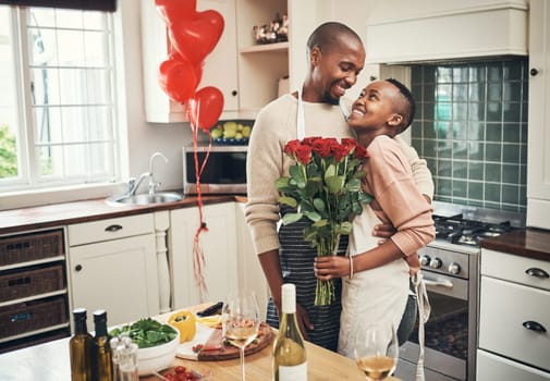 Flowers, love and valentines day with a black couple in the kitchen for a romantic celebration together. Food, gift or romance with a man and woman bonding in their home during a special event.