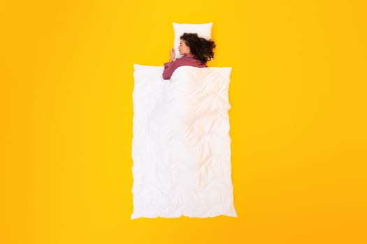 Woman Snoozing Covered With Blanket Over Yellow Background, Above View