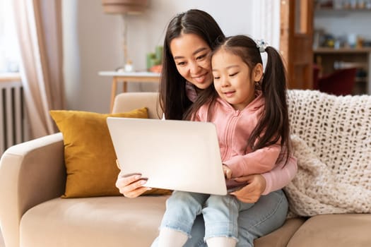 Happy Asian Mommy And Little Daughter Using Laptop At Home