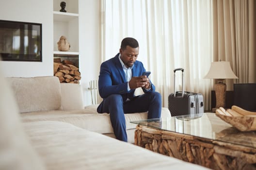 African businessman on phone in hotel room, reading email on smartphone and corporate professional in Chicago. Black entrepreneur typing message, luxury accommodation in city and hospitality travel