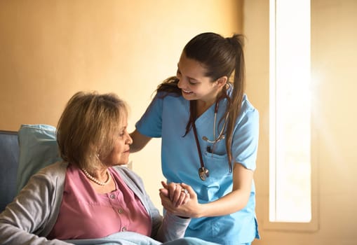 Can I help you up. a caregiver assisting a senior patient in a nursing home.