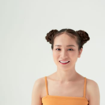 Modern playful girl with two hair buns smiling looking up dreamily. 