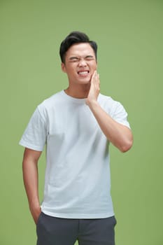 Young man suffering from toothache and holding his cheek, dental concept