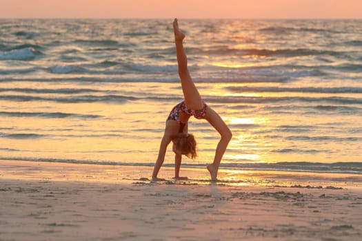 Teen girl doing yoga on the beach
