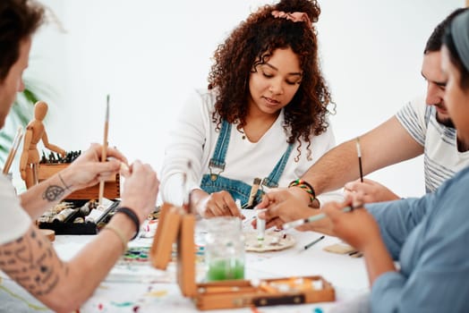 A sense of belonging lives within art. a diverse group of artists sitting together and painting during an art class in a studio.