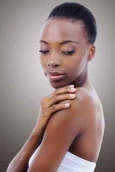 She has flawless skin. A beautiful African woman looking down at her bare shoulder.