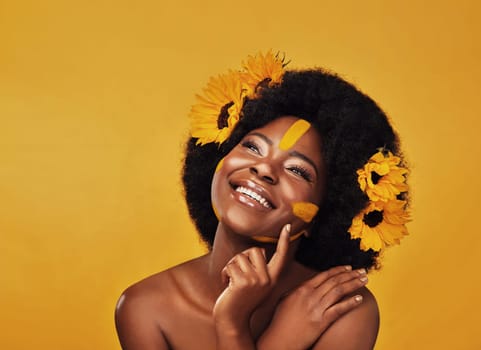 Thinking, beauty and happy black woman with sunflower in studio for makeup or wellness on yellow background. Flower, skincare and African lady model smile, relax or contemplate eco friendly treatment